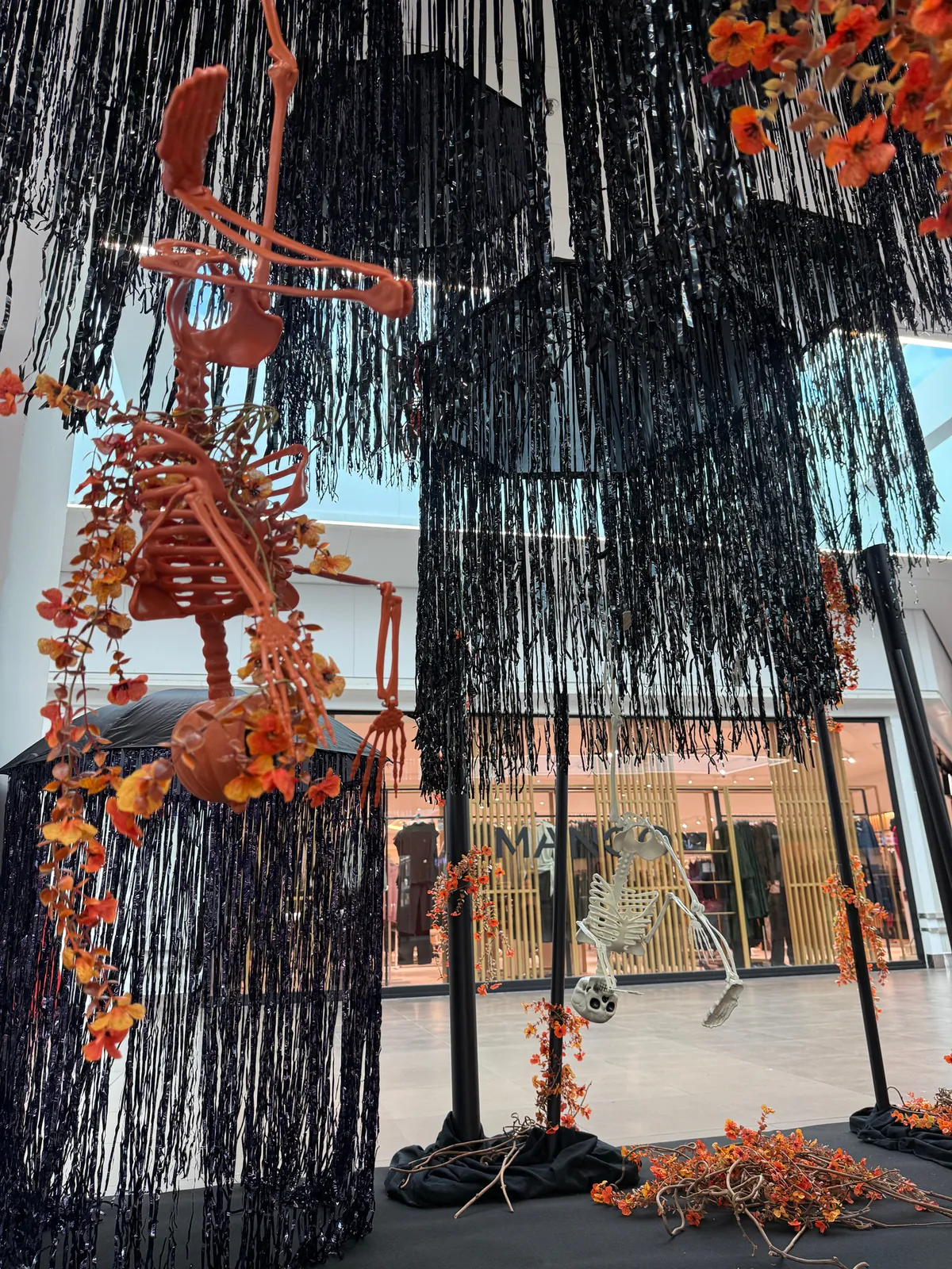 Squelette orange suspendu entre des franges noires pour Halloween