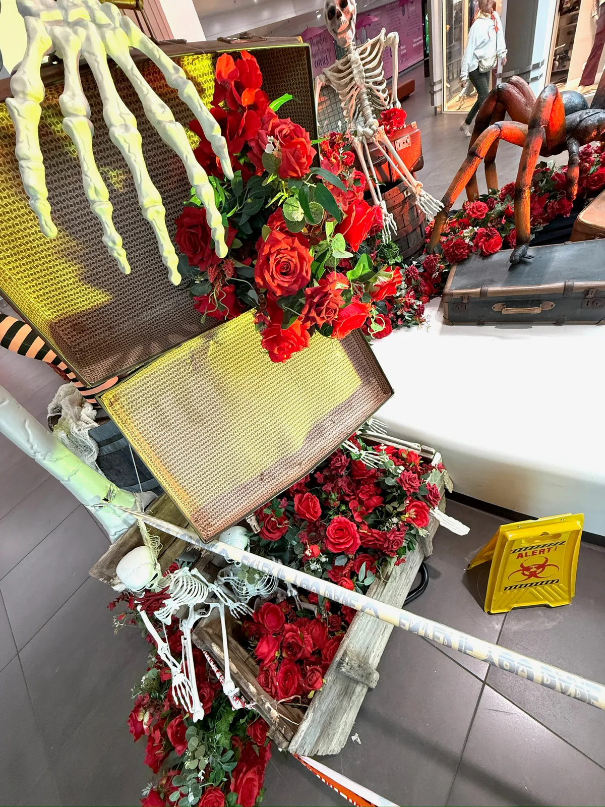 Main de squelette et roses rouges sur une valise, détail du décor Halloween
